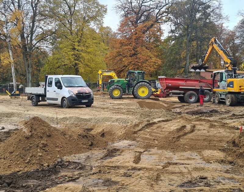 Baufahrzeuge auf dem Gelände des Tierparkes. Bagger befüllen einen Anhänger mit Erde.