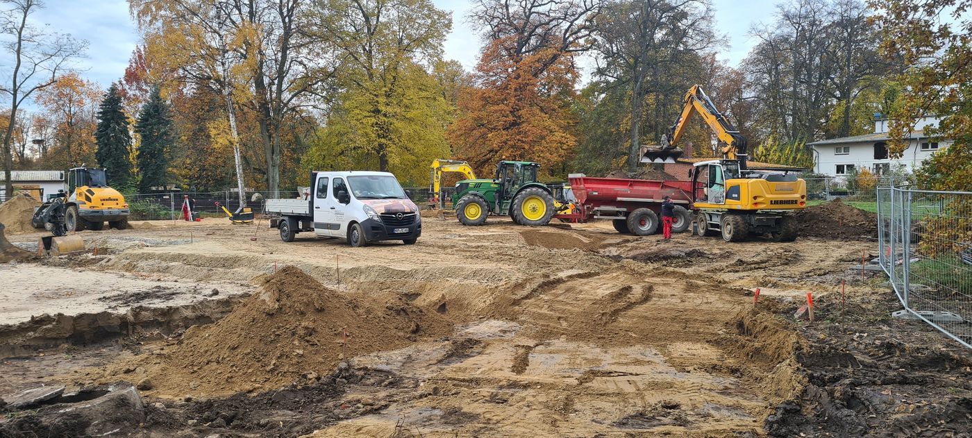 Baufahrzeuge auf dem Gelände des Tierparkes. Bagger befüllen einen Anhänger mit Erde.