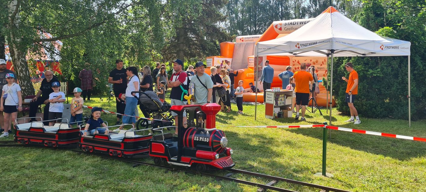 Kinder toben in der Hüpfburg und fahren mit der Kindereisenbahn.