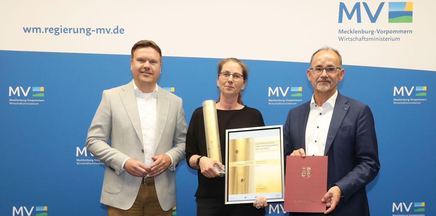 Mareen Buchholz erhält den Preis von Wirtschaftsminister Wolfgang Blank. Sie lächelt mit der Urkunde in der Hand in die Kamera.