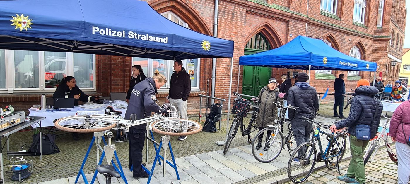 Beamte kommen am Informationsstand der Polizei mit Einwohnern ins Gespräch. Sie informieren über die Fahrradcodierung an diesem Tag.