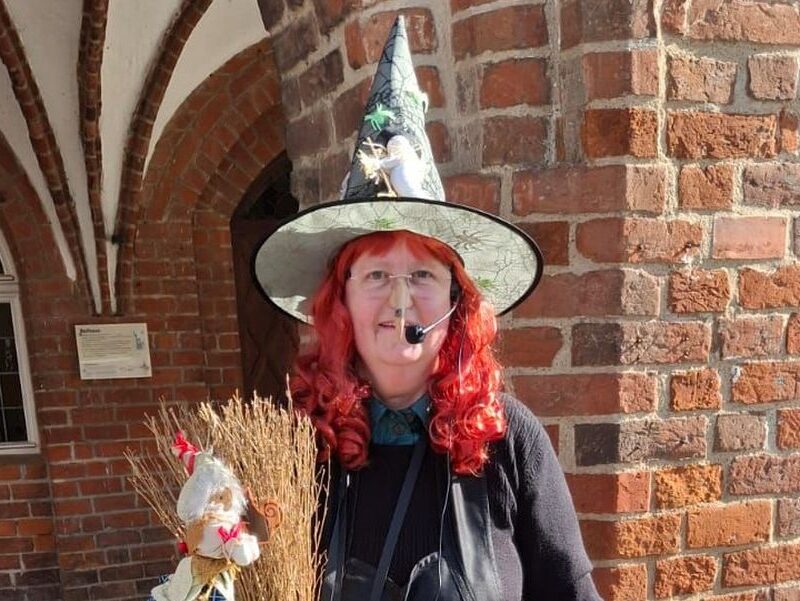 Stadtführerin Gudrun Rech als Hexe verkleidet vor dem Grimmener Rathaus.