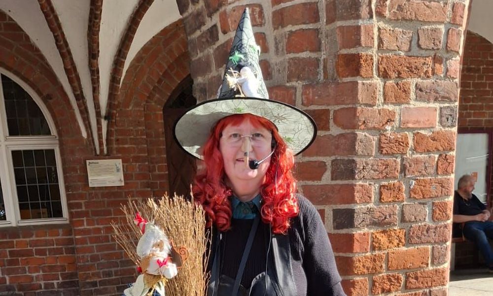 Stadtführerin Gudrun Rech als Hexe verkleidet vor dem Grimmener Rathaus.