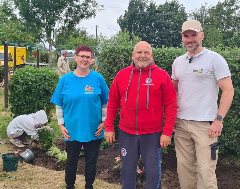 Naturbadchef Mario Gohs, Fördervereinsvorsitzende Carmen Wiedemann und Sebastian Kalden von der Stiftung Klima- und Umweltschutz MV, stehen vor einer Hecke im Schwimmbad.