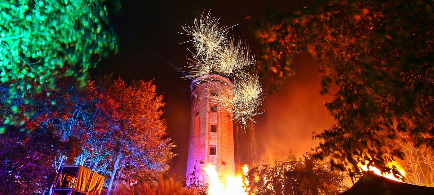 Grimmener Wasserturm im bunten Scheinwerferlicht. Zu sehen sind pyrotechnische Effekte des Feuerwerkes.