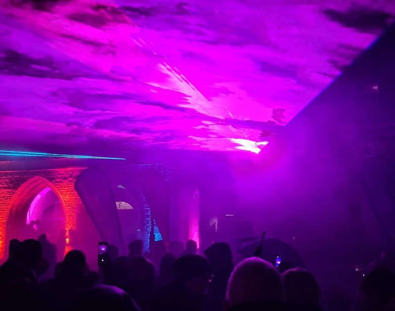 Lasershow auf dem Marktplatz. Zu sehen ist ein bunter Lichtkegel in dem Menschen stehen.