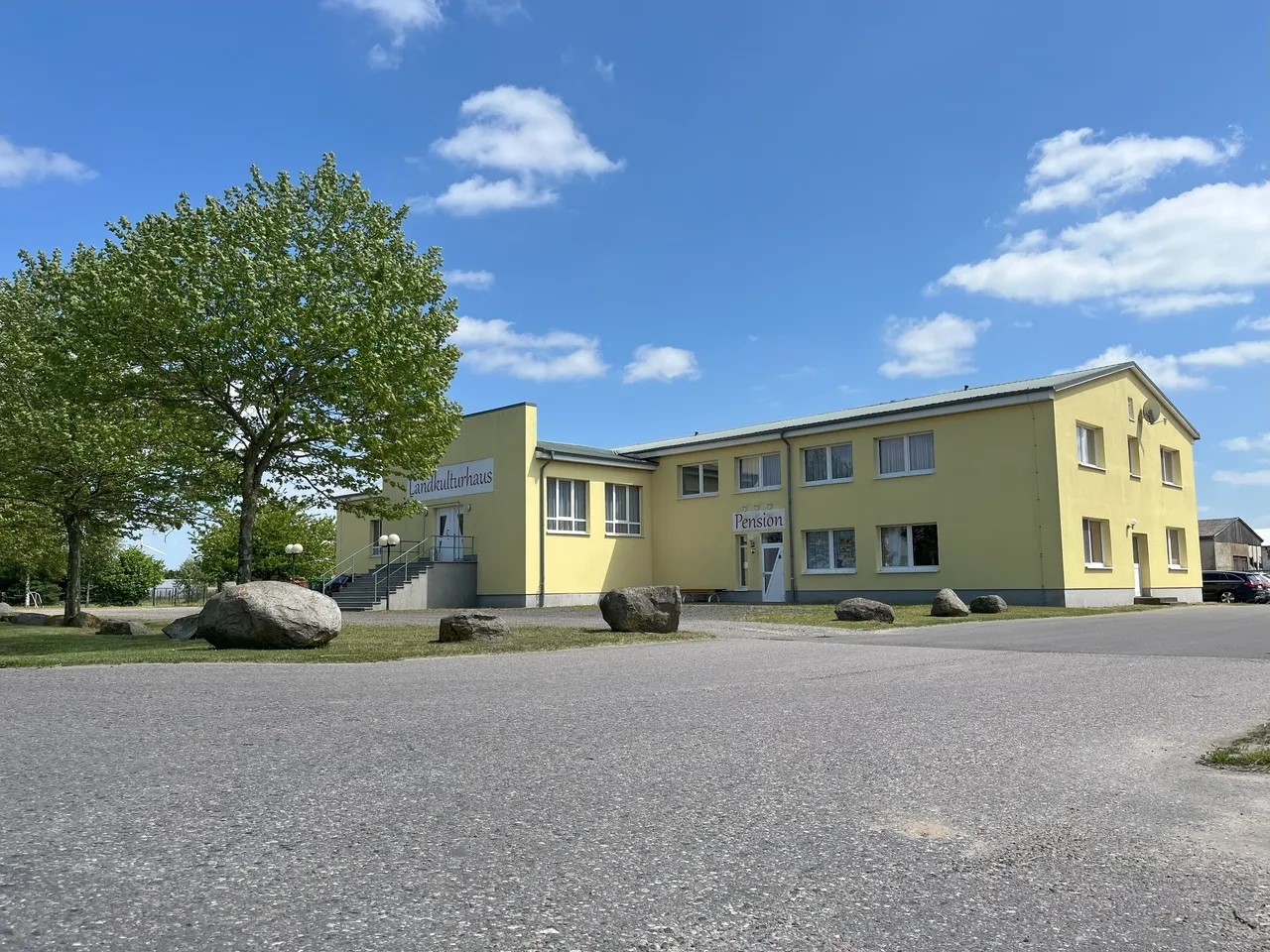 Pension Leyerhof mit gelber Fassade und großen Steinen und Bäumen und ein Parkplatz