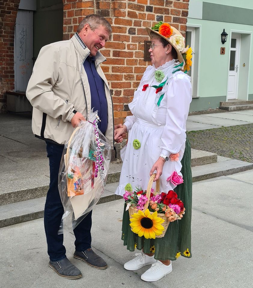Bürgermeister Marco Jahns gratuliert vor dem Rathaus Gudrun Rech und überreicht ein Präsent.