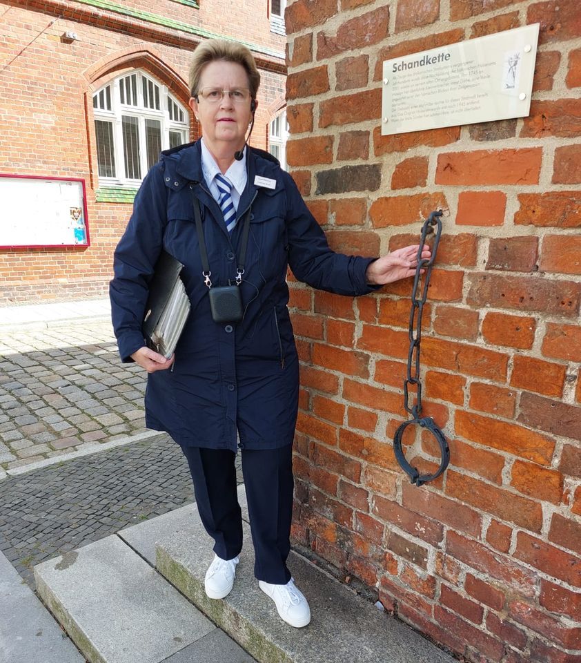 Gudrun Rech steht am Rathaus und hält an einem Pfeiler die Schandkette in der Hand.