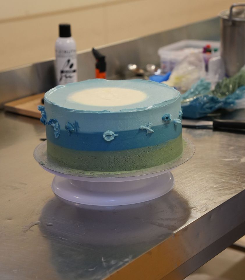 Erste Verzierungen werden an der Torte angebracht. Sie ist in unterschiedlichen Blautönen gehalten.